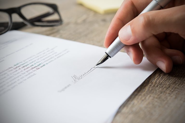 Close-up of businessman signing legal contract document, representing professional business and corporate legal services in Fort Lauderdale