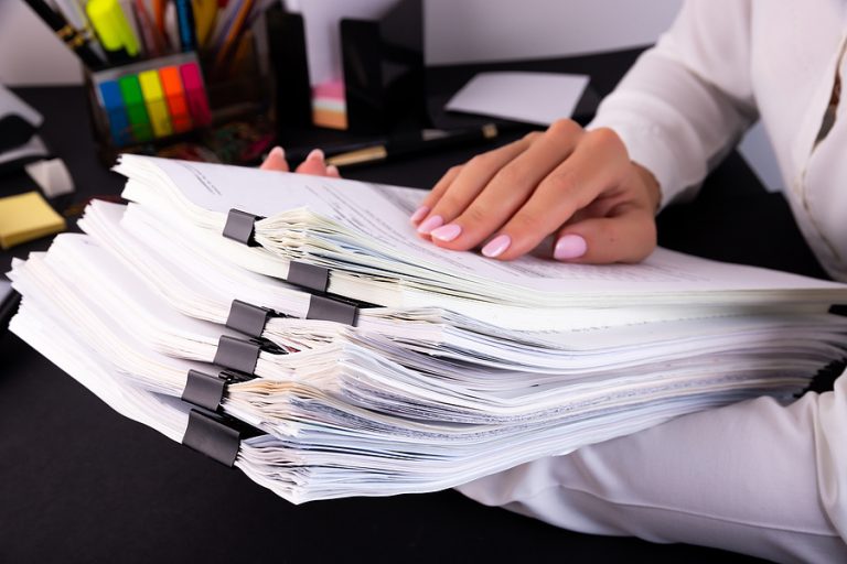 Professional businesswoman organizing important legal documents and death benefit claims paperwork, representing estate and insurance law services in Boca Raton