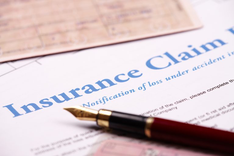 Blank insurance claim form with identification documents and vehicle papers on desk, representing comprehensive insurance claim services in Fort Lauderdale